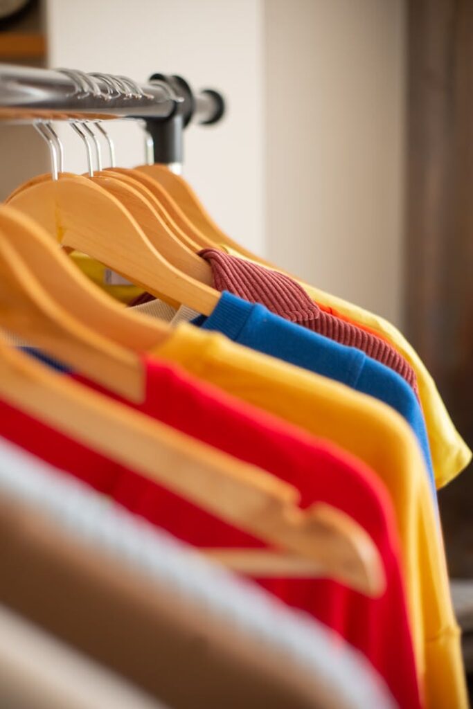 Vividly colored t-shirts arranged neatly on wooden hangers for a vibrant fashion display.